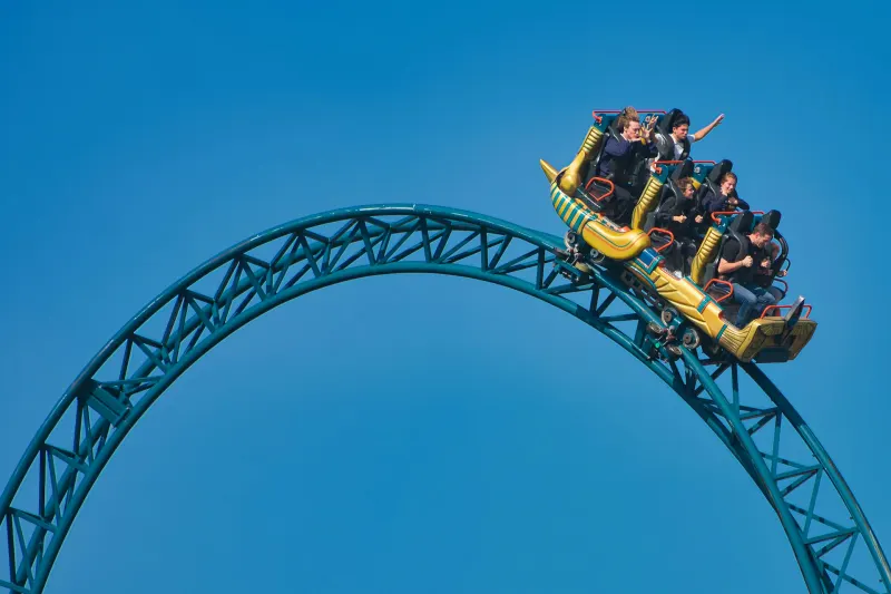 Riders on a roller coaster loop against a blue sky