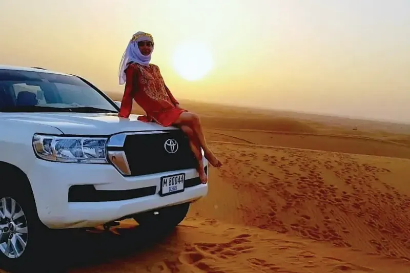 Guest sitting on a Land Cruiser in the Dubai desert on a morning desert safari