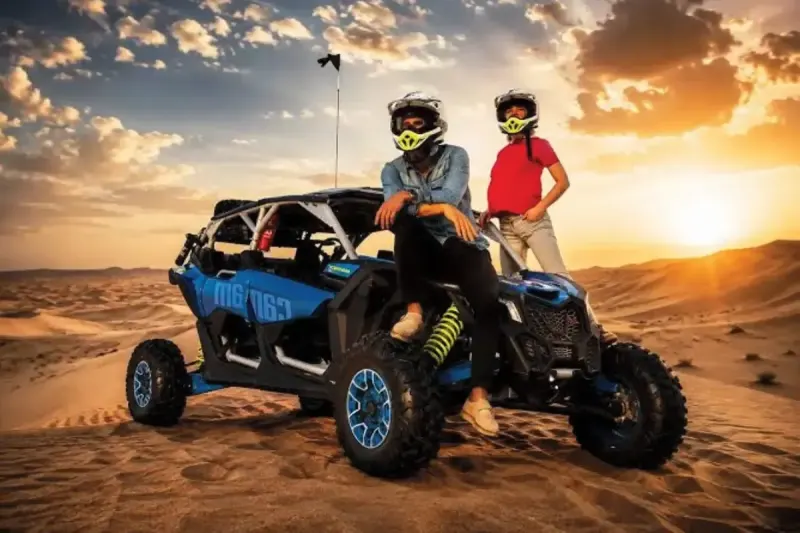 Can-Am Maverick X3 turbo dune buggy on a high dune in Dubai at sunset
