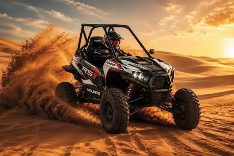 Polaris RZR 1000cc single seater dune buggy kicking up sand in the Dubai desert