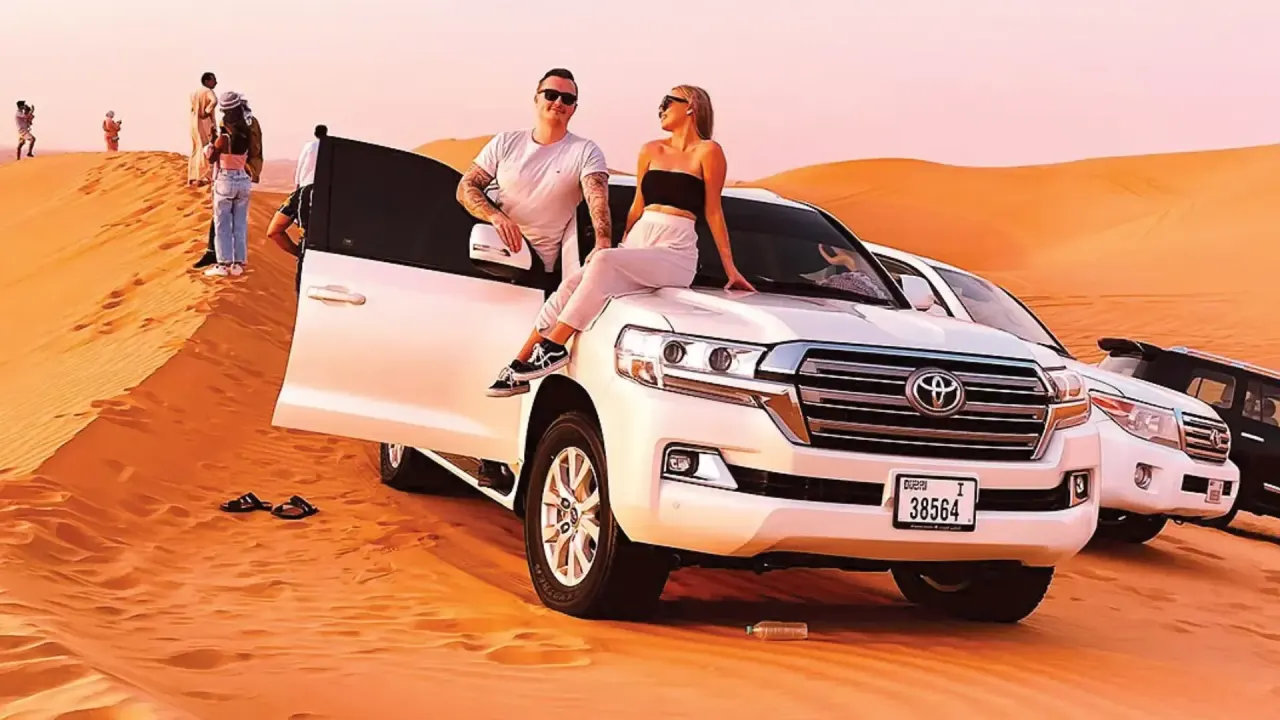 Couple relaxing on a Land Cruiser on the red dunes during a Dubai desert safari